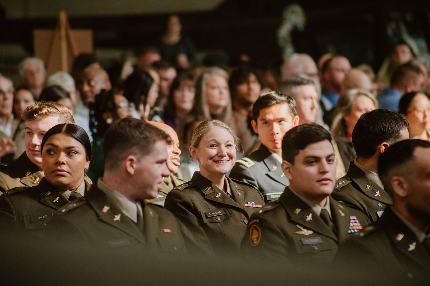 Dark auditorium filled with military service members during presentation.