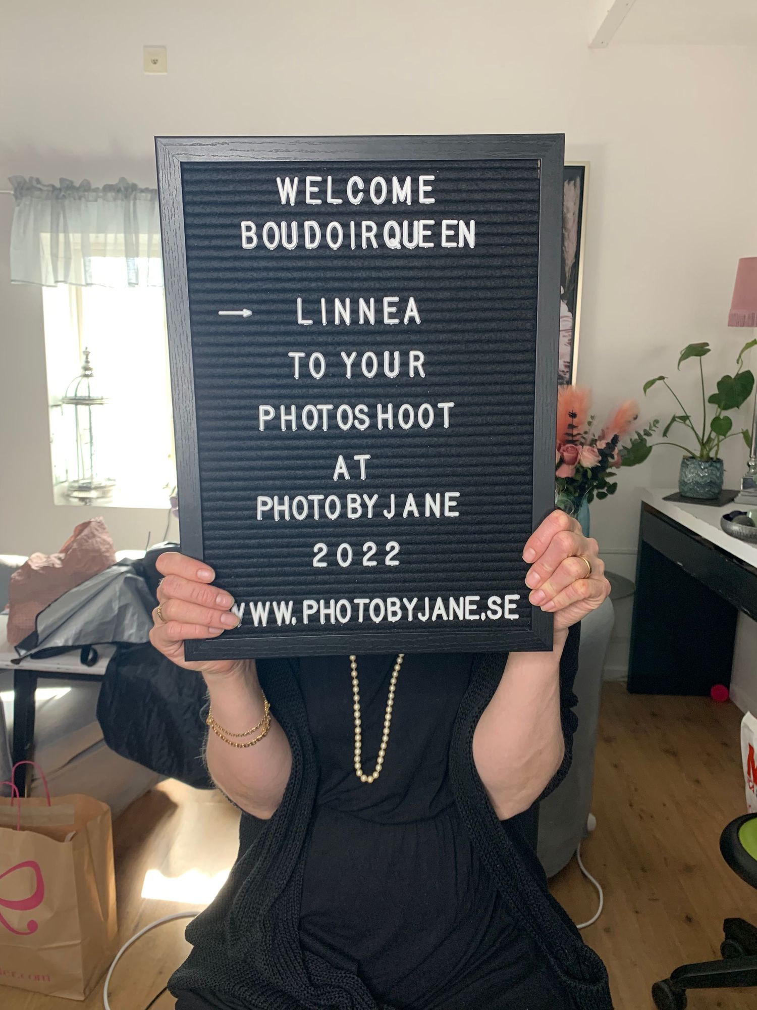 Anonym kund sitter med en bokstavstavla som välkomnar min boudoir morgongåva kund innan sin fotografering i min studio.
