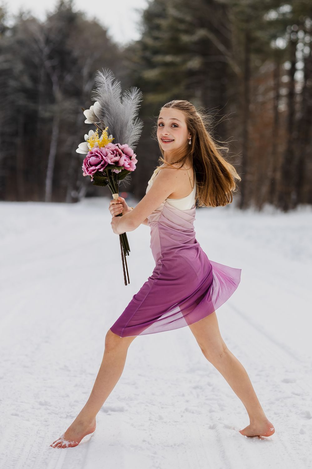 A dancer in a purple dress performs graceful movements in the snow, creating a dynamic winter dance sequence.