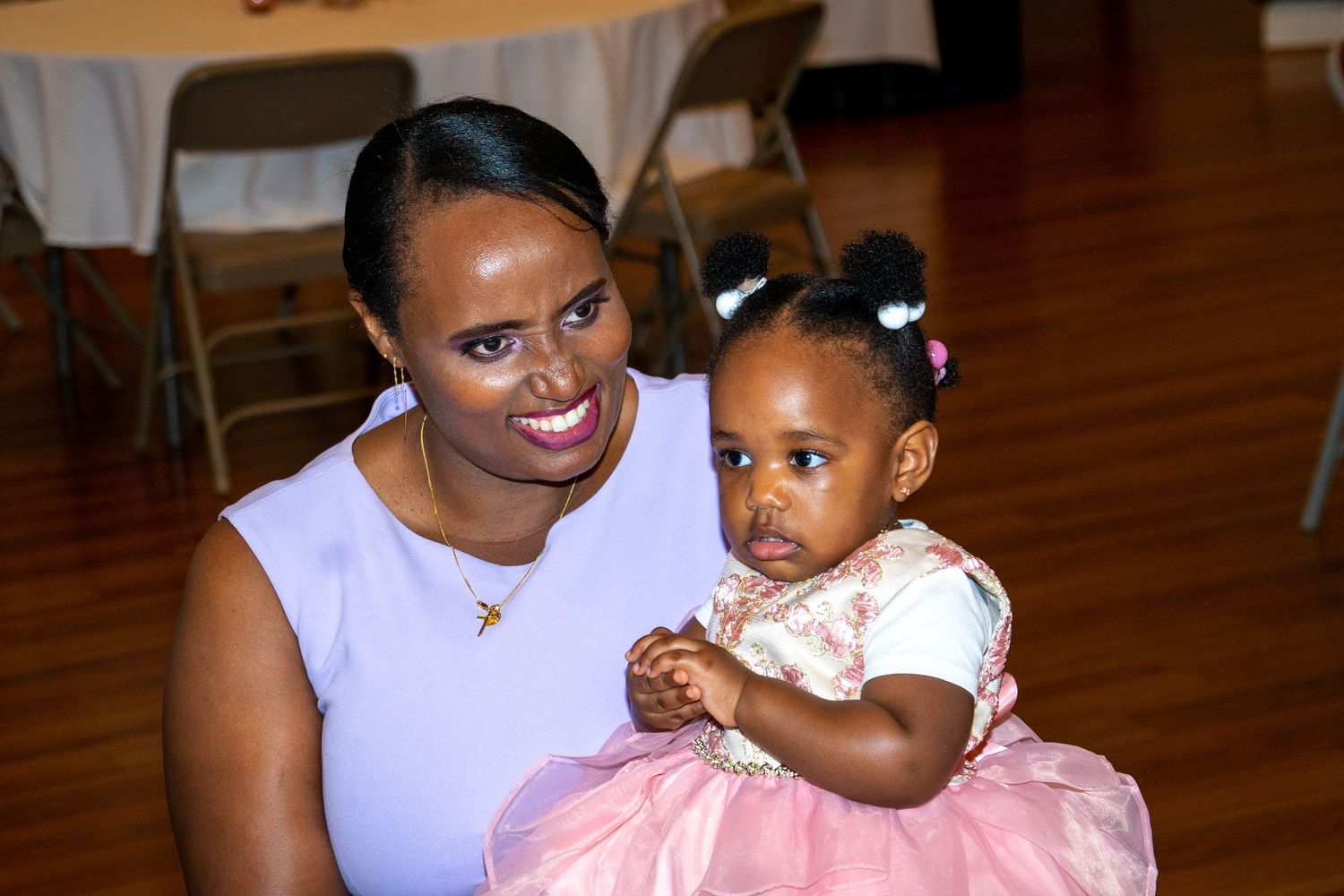 An adult and child in formal attire share a tender moment at what appears to be a celebration.