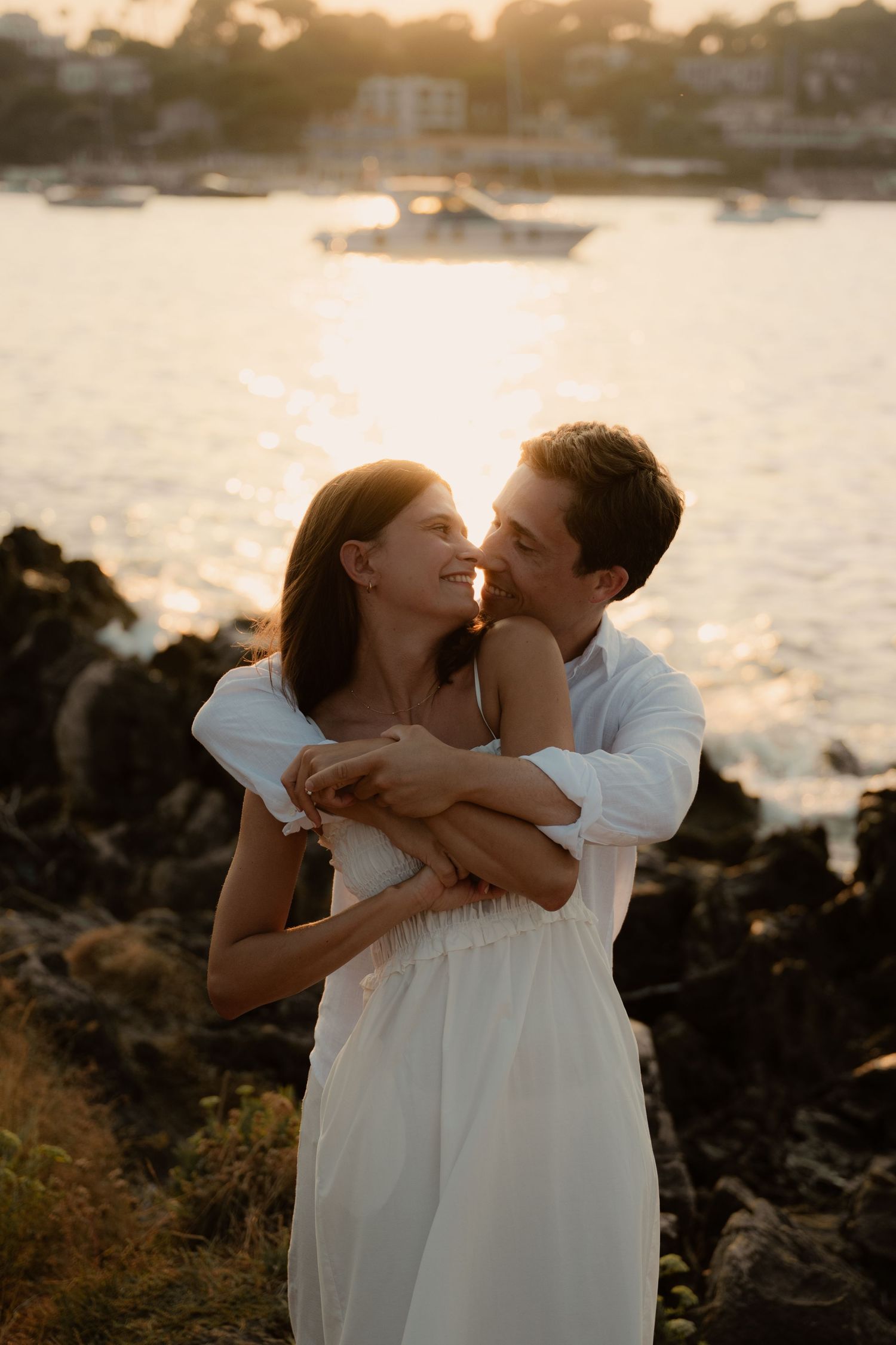 Homme qui enlace sa femme en l'embrassant au sentier du cap d'Antibes au coucher du soleil