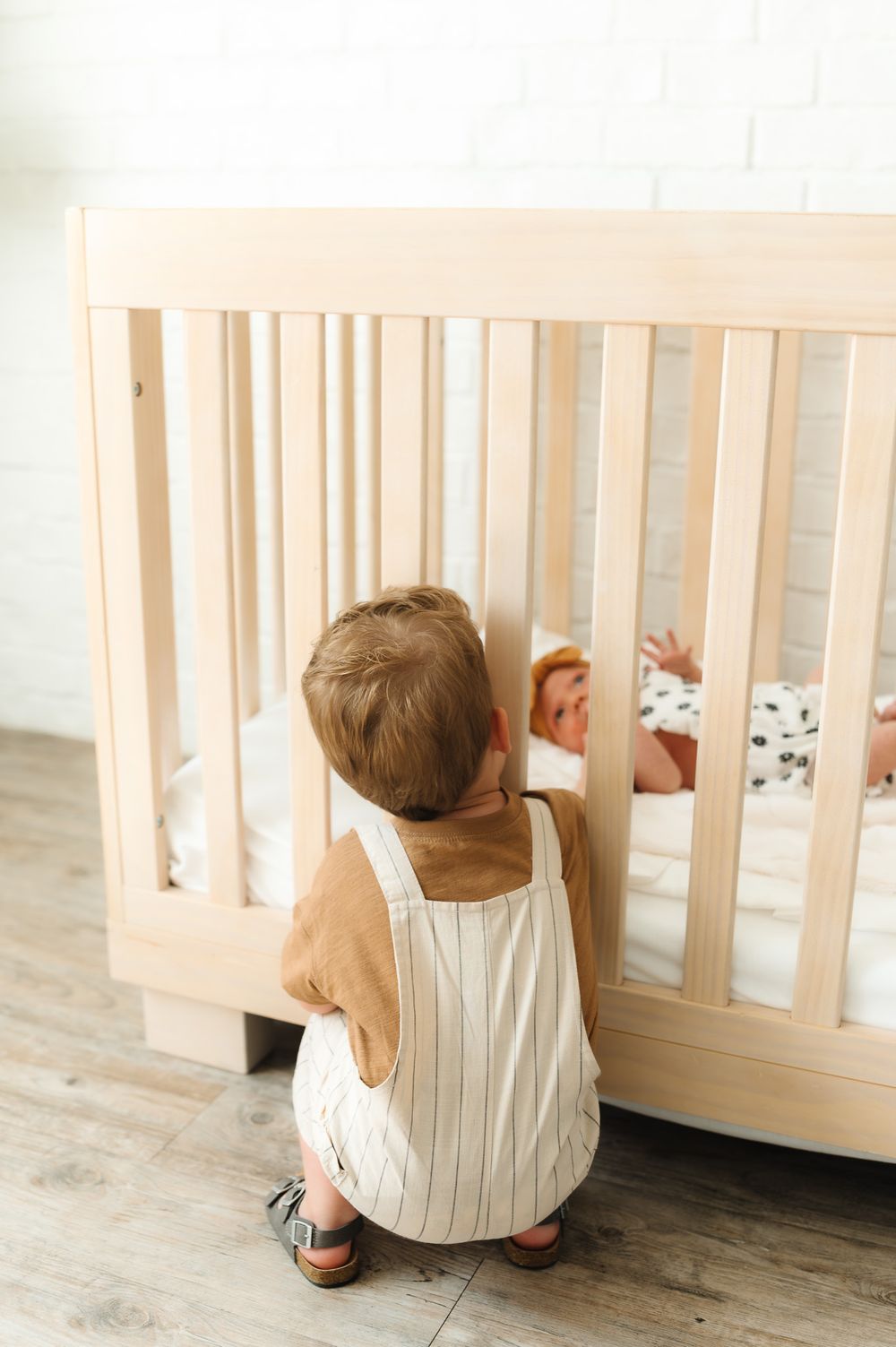 Small child peering through wooden crib slats from behind in a sequence of curious poses.