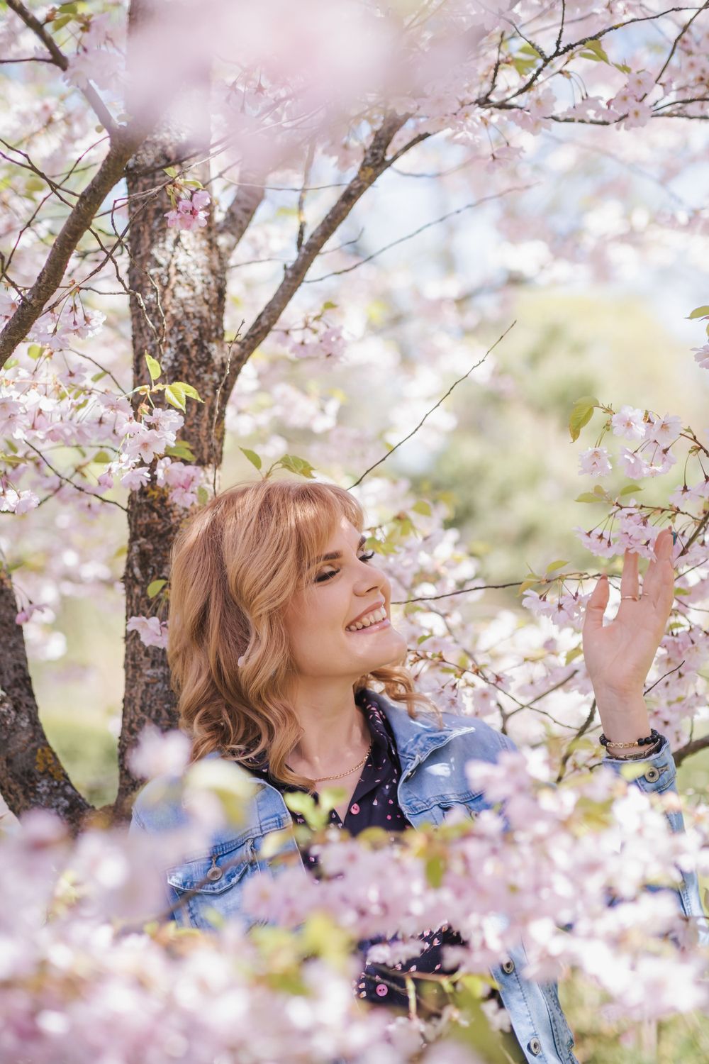 A joyful spring moment surrounded by delicate cherry blossoms and soft pink petals in natural sunlight.