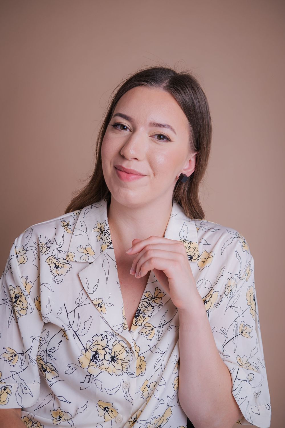 Portrait of someone in a floral patterned robe against a warm brown background with a gentle expression.