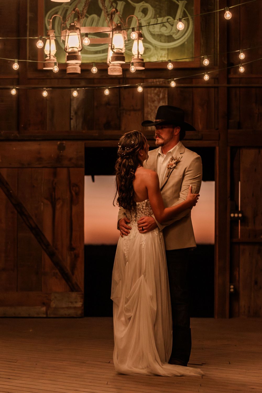 First dance in rustic barn venue with romantic string light ambiance.