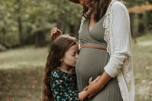 A maternity photoshoot in a natural outdoor setting with autumn colors and soft lighting.