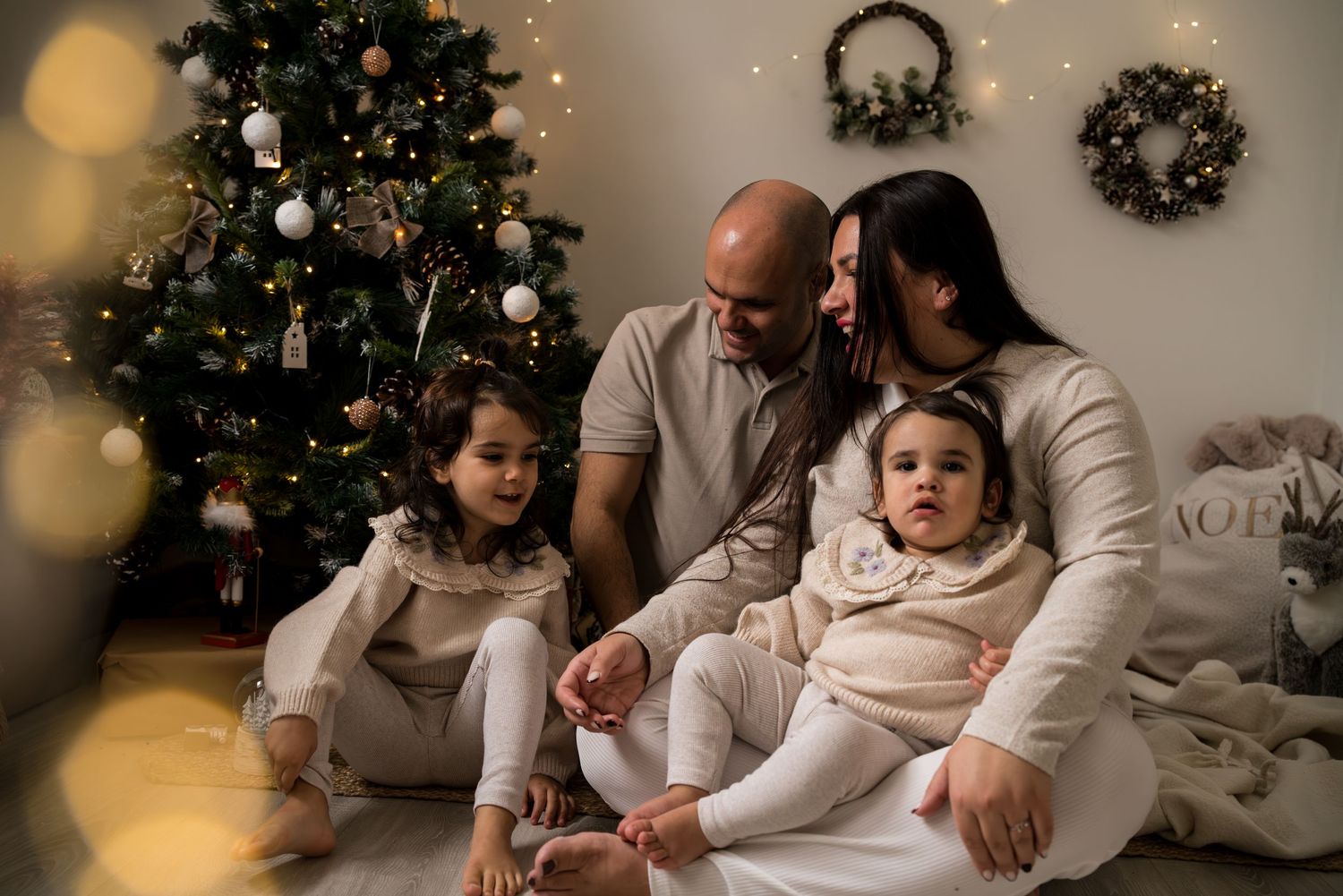 photo de famille pendant une seance photo de noel, la maman et le papa regarde tendrement leur enfant