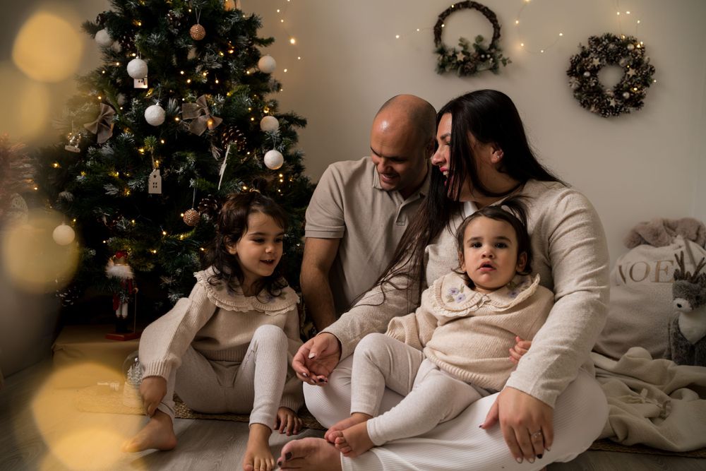 photo de famille pendant une seance photo de noel, la maman et le papa regarde tendrement leur enfant