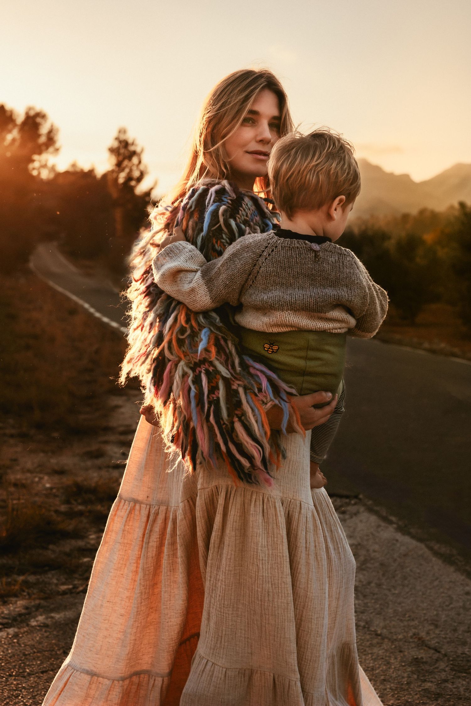 A sunset scene in Javea  on a dirt road with two figures embracing, wearing boho style clothing in warm golden light. Javea photographer