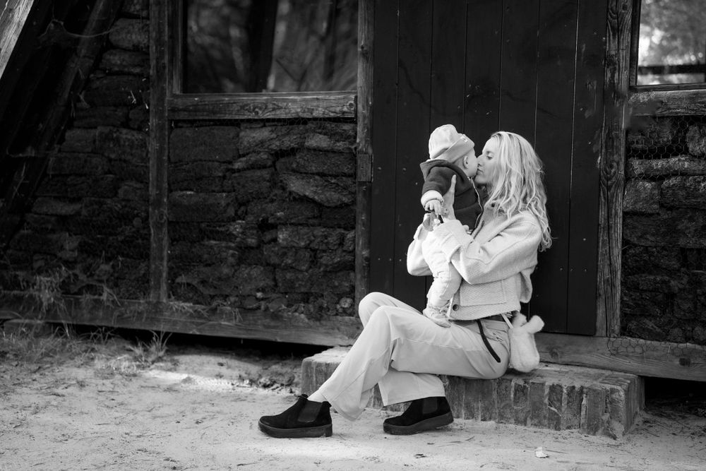 Schwarz-Weiß-Fotoserie, die intime Familienmomente in rustikalen Hüttenstrukturen zeigt.
