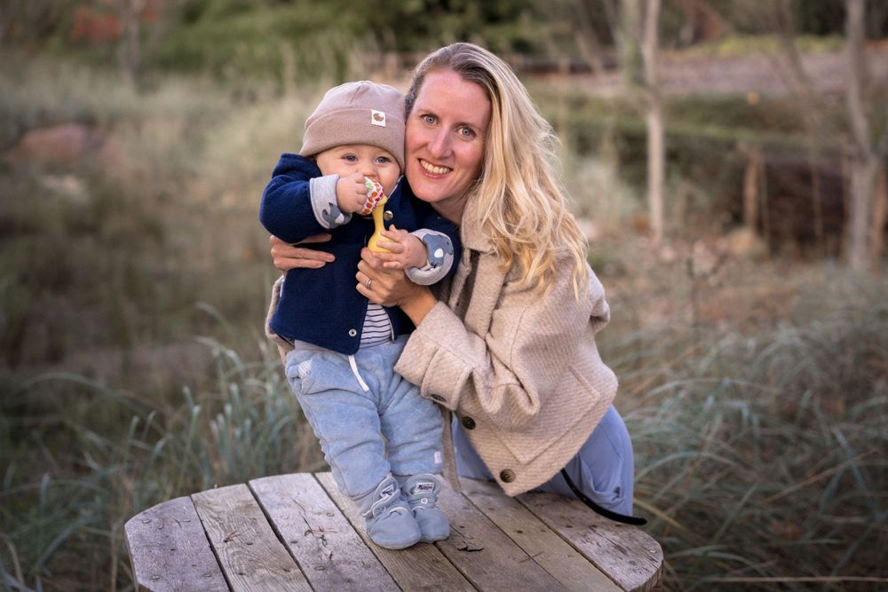 Ungestellter Familienmoment im Freien auf einer Holzplattform mit natürlichem Hintergrund.