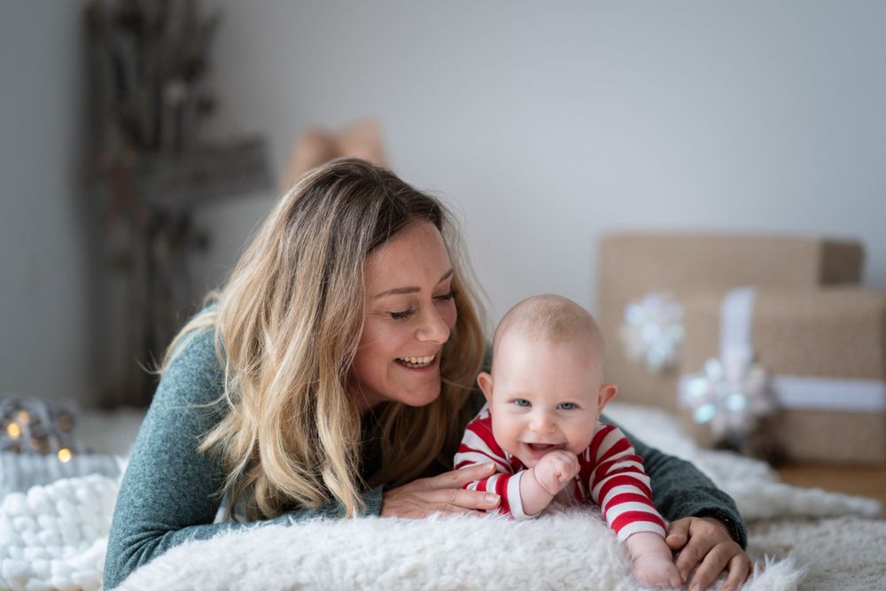 Mutter und Baby erleben zärtliche Momente beim gemeinsamen Spielen auf weißem Kissen.