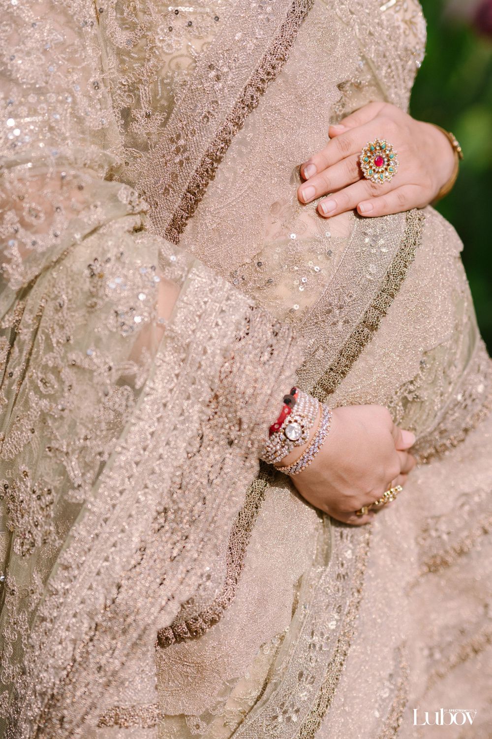 Close-up of intricate beadwork and jewelry details on champagne-colored fabric.