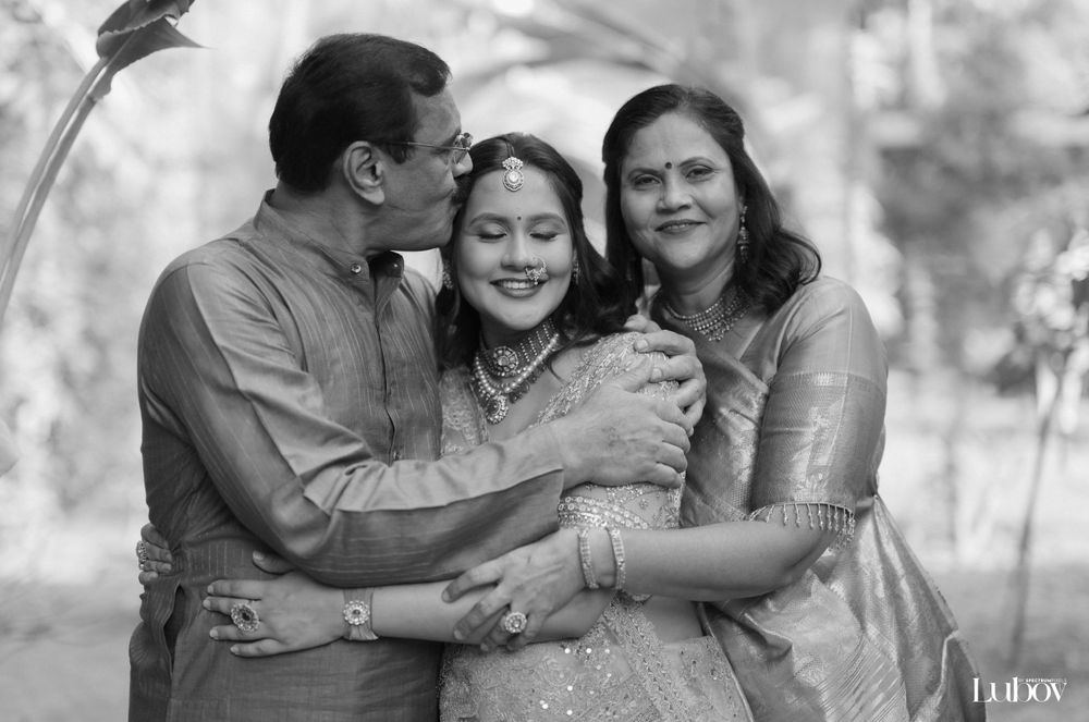 Three people share an intimate moment in traditional Indian attire captured in black and white.