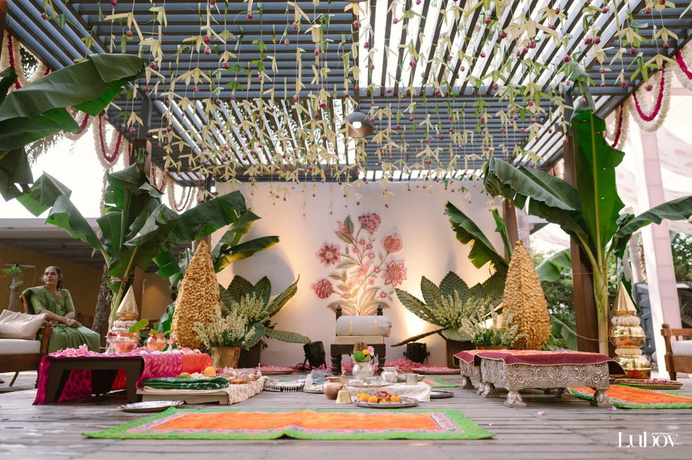 An elegant Indian wedding reception setup with golden trees and tropical decor under string lights.