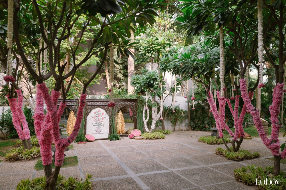 Courtyard garden path lined with pink-wrapped trees and ornate architectural details.