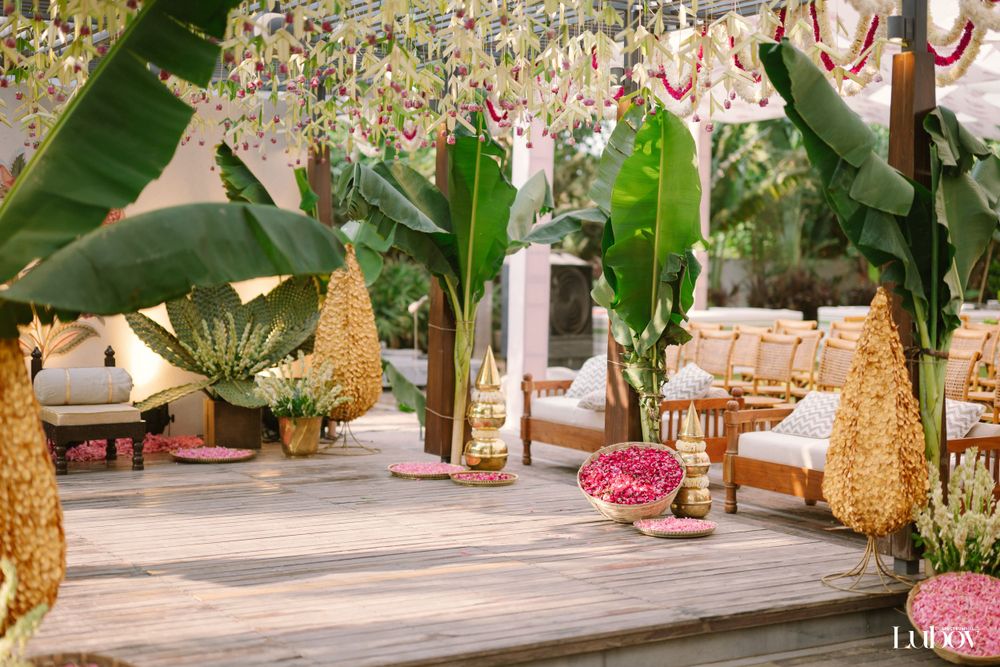 Tropical garden setting with banana plants, gold decorations, and wooden furniture on a deck.