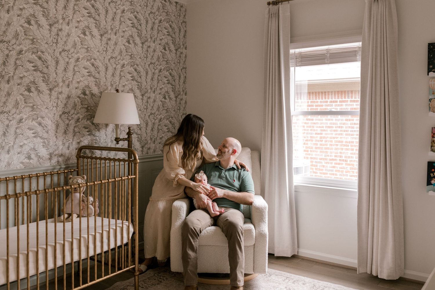 Mother and baby share intimate moment in cozy nursery with floral wallpaper.