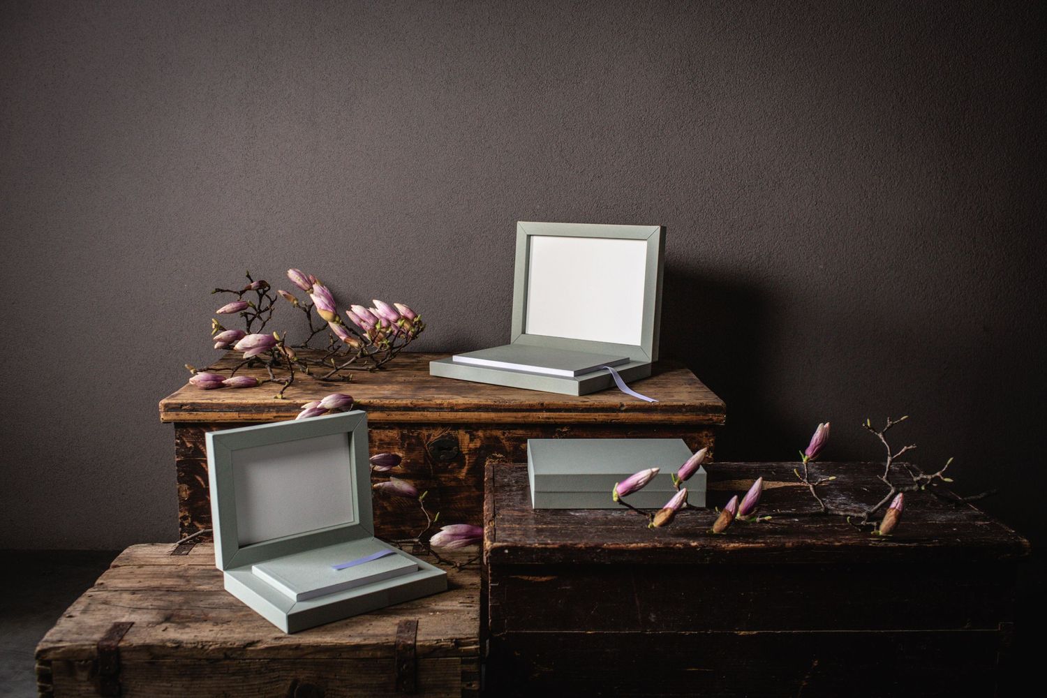Minimalist photo album boxes displayed on dark wooden surface with moody lighting.