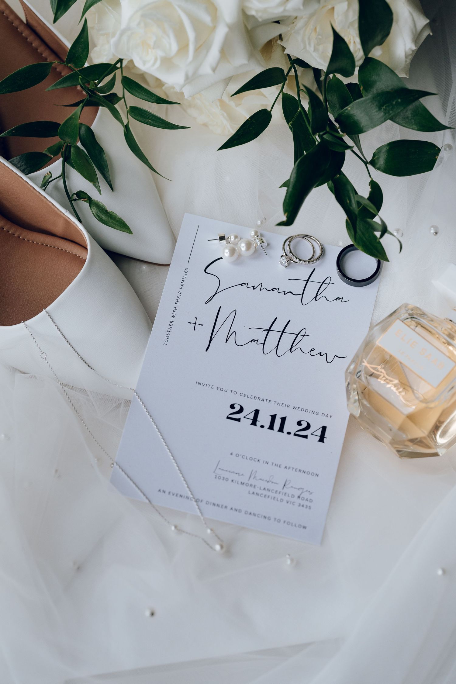 Wedding invitation with white flowers and perfume bottle on light background.