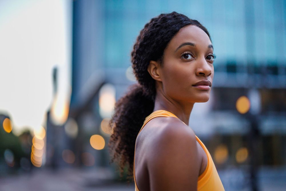 Portrait of a person in yellow top against urban evening background with bokeh lights.