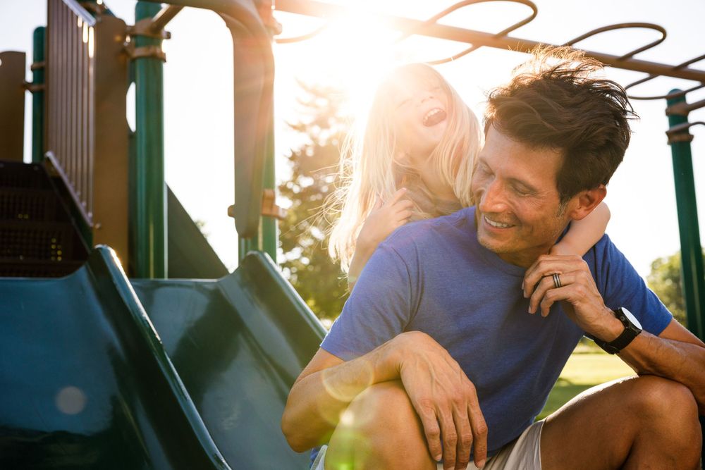 Couple sharing playful moment on playground equipment during sunset.