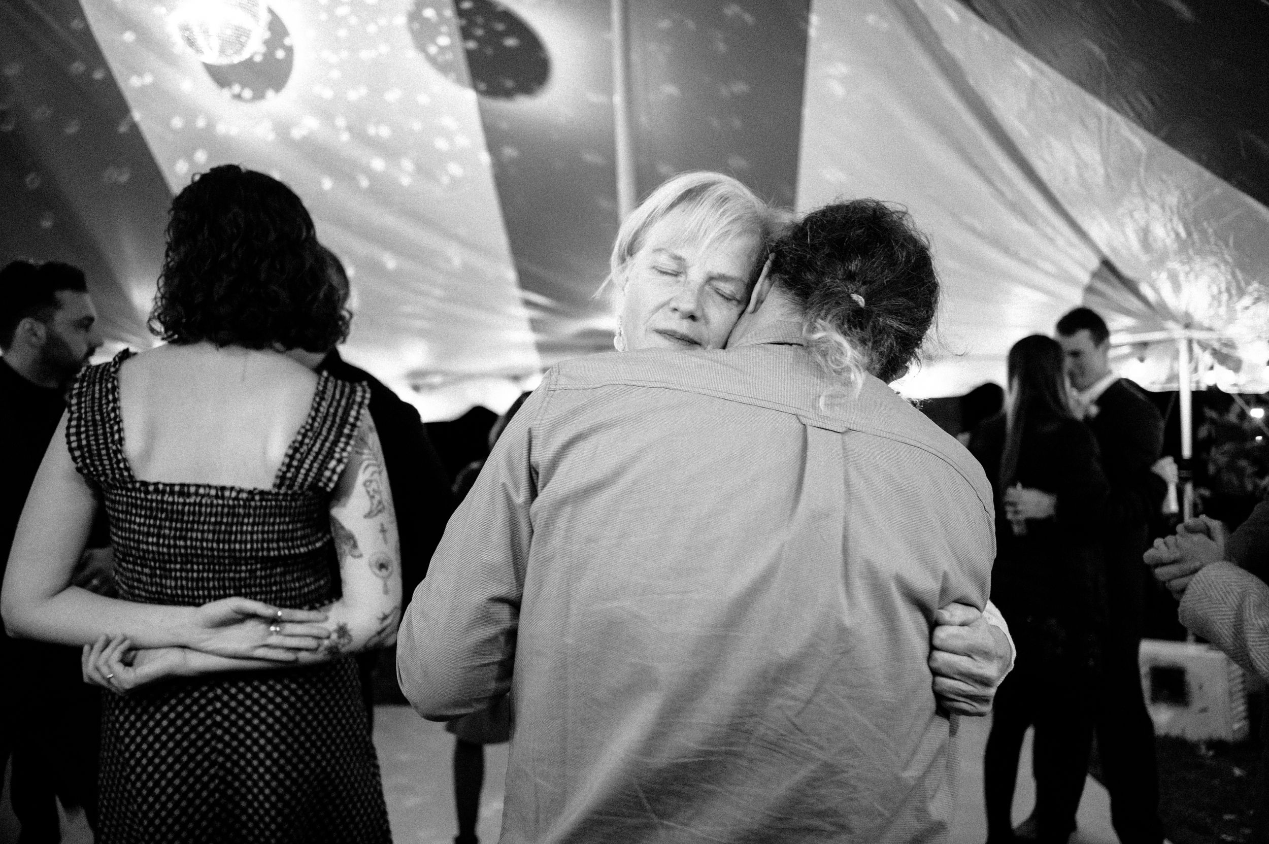 Black and white photo of two people sharing a warm embrace on a dance floor.