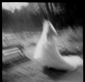 Blurred artistic black and white photo of bride in wedding gown outdoors.