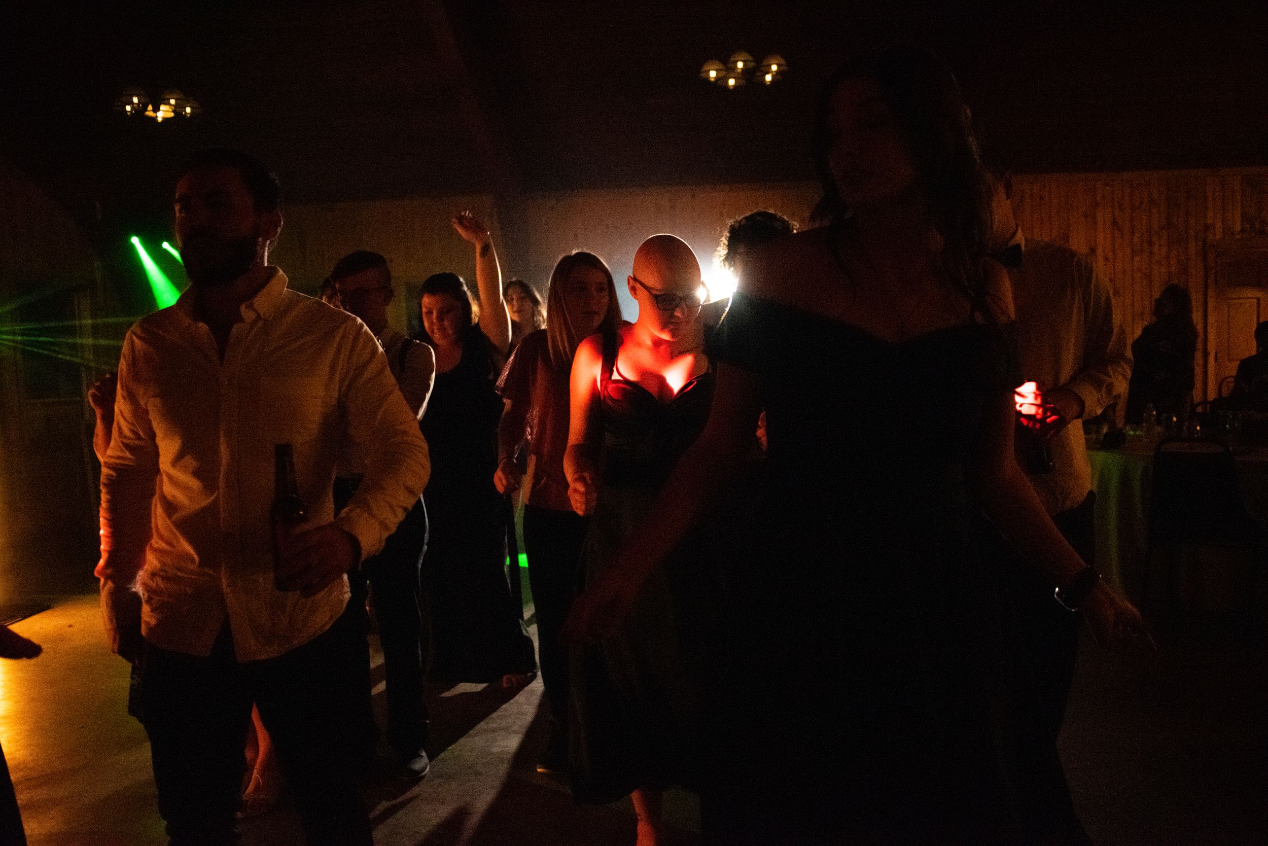 Guests dancing under colorful lights at a dark wedding reception.