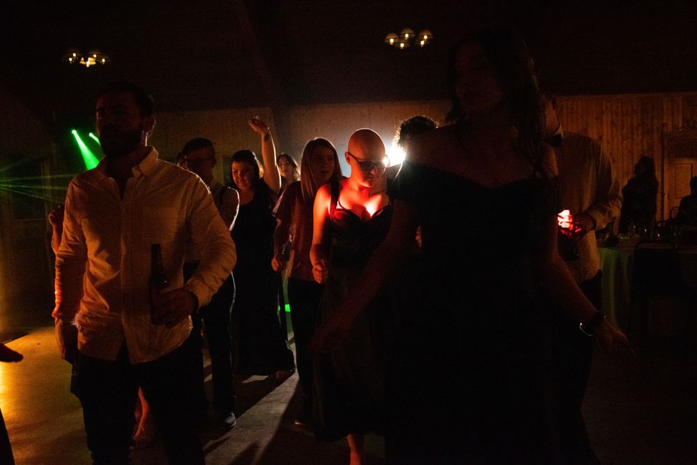 Guests dancing under colorful lights at a dark wedding reception.