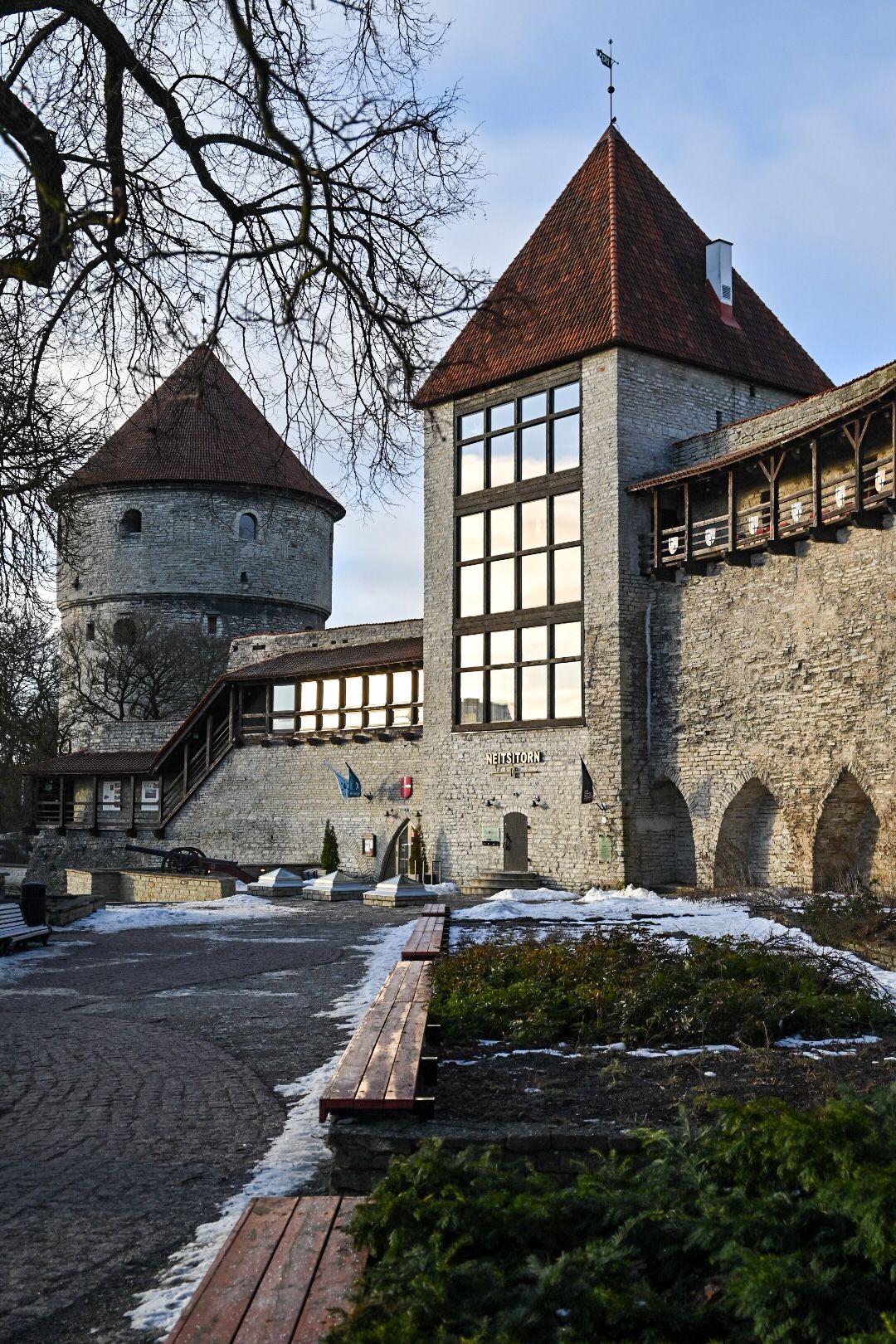 Medieval fortress walls with defensive towers and timber-framed architecture covered in light snow.