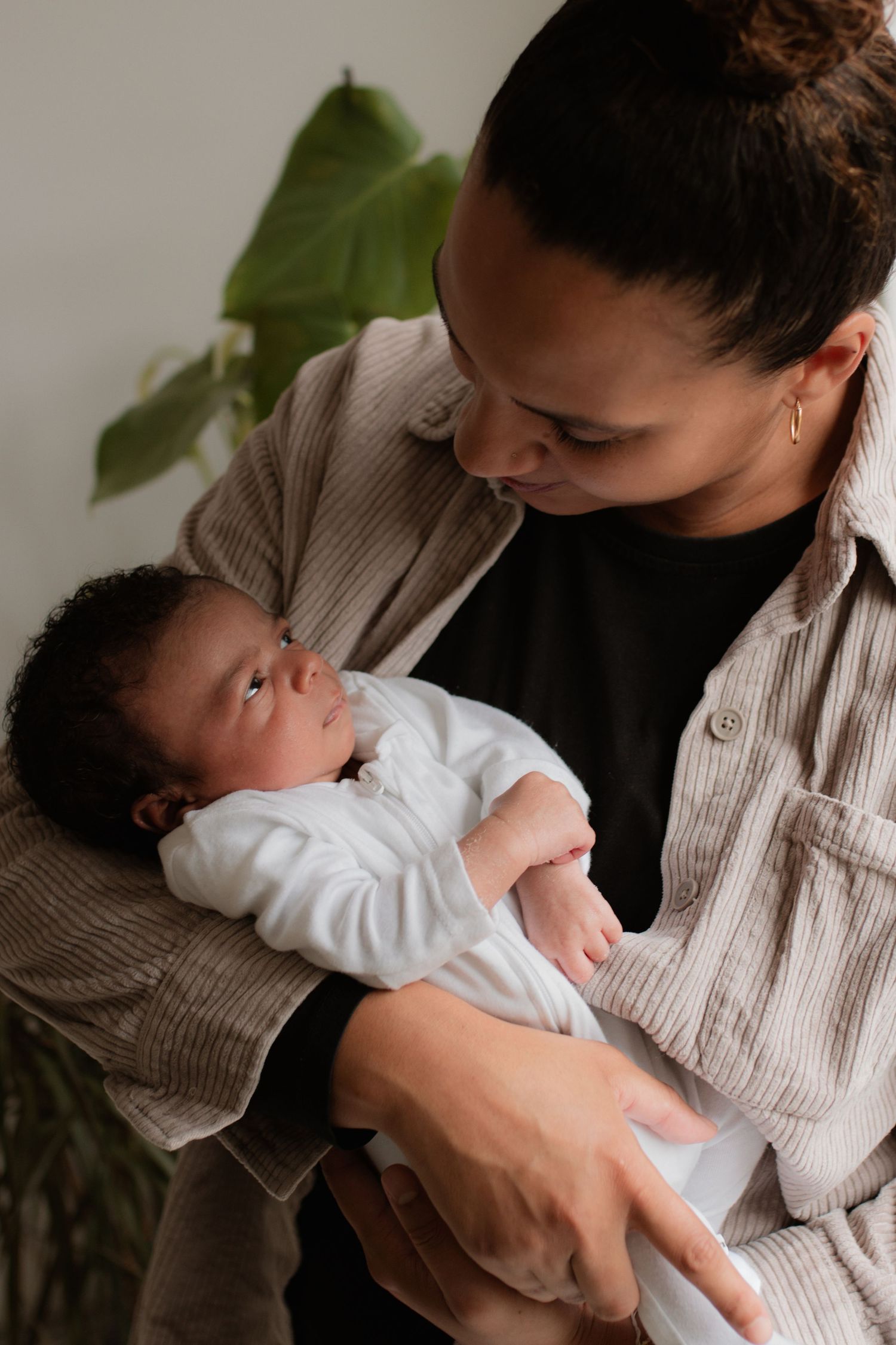 Gentle nurturing moments captured between family members and infant in soft lighting.