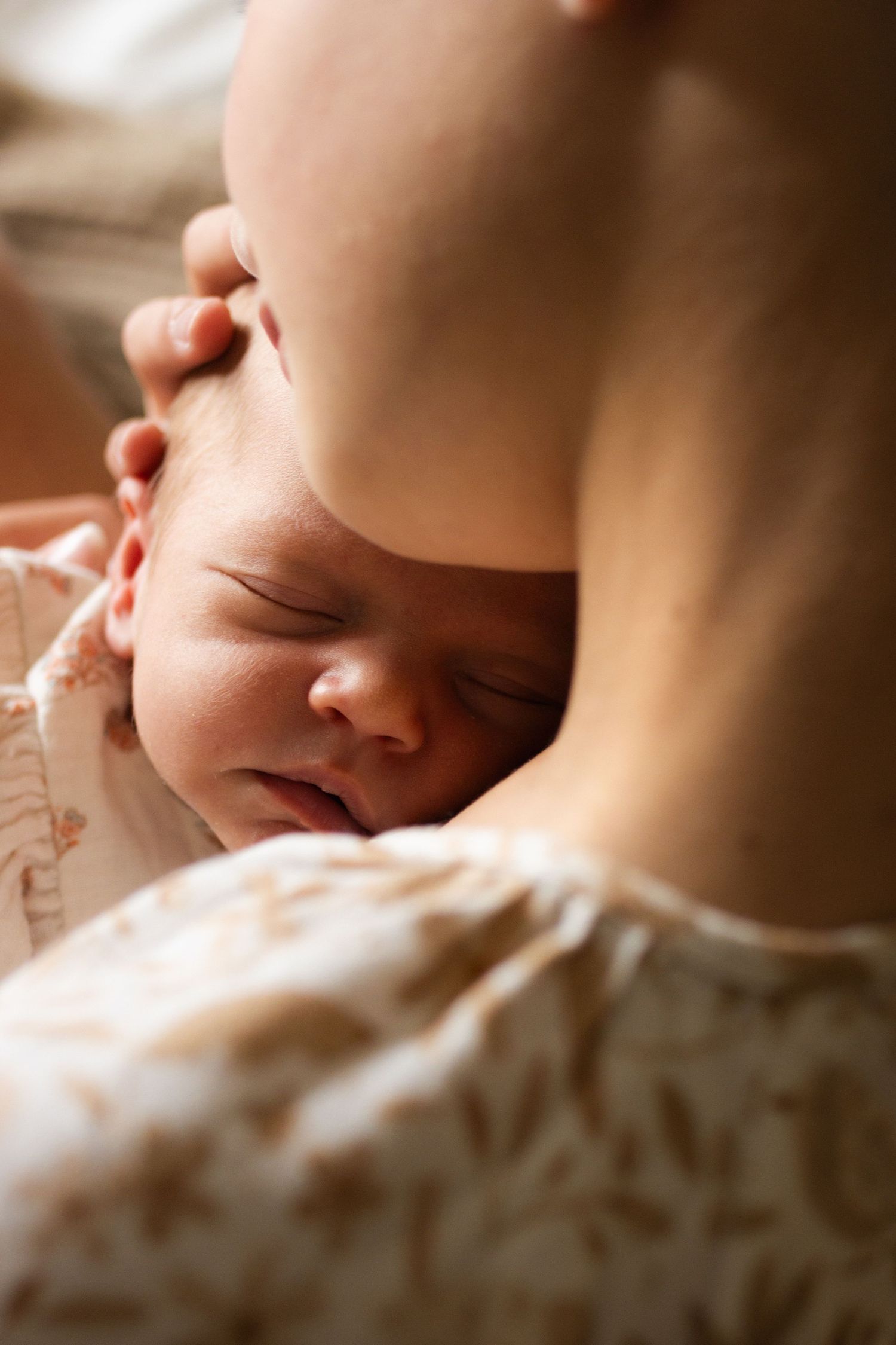 Peaceful sleeping newborn photographed in soft, intimate lighting.