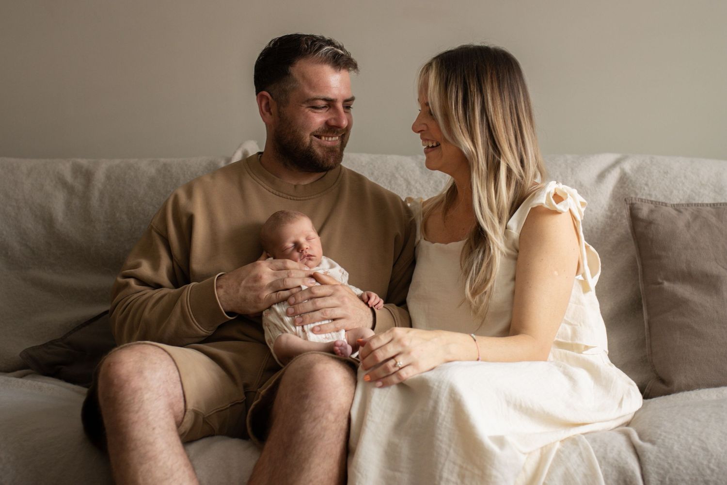 Family sharing tender moments with their newborn on a comfortable white couch.