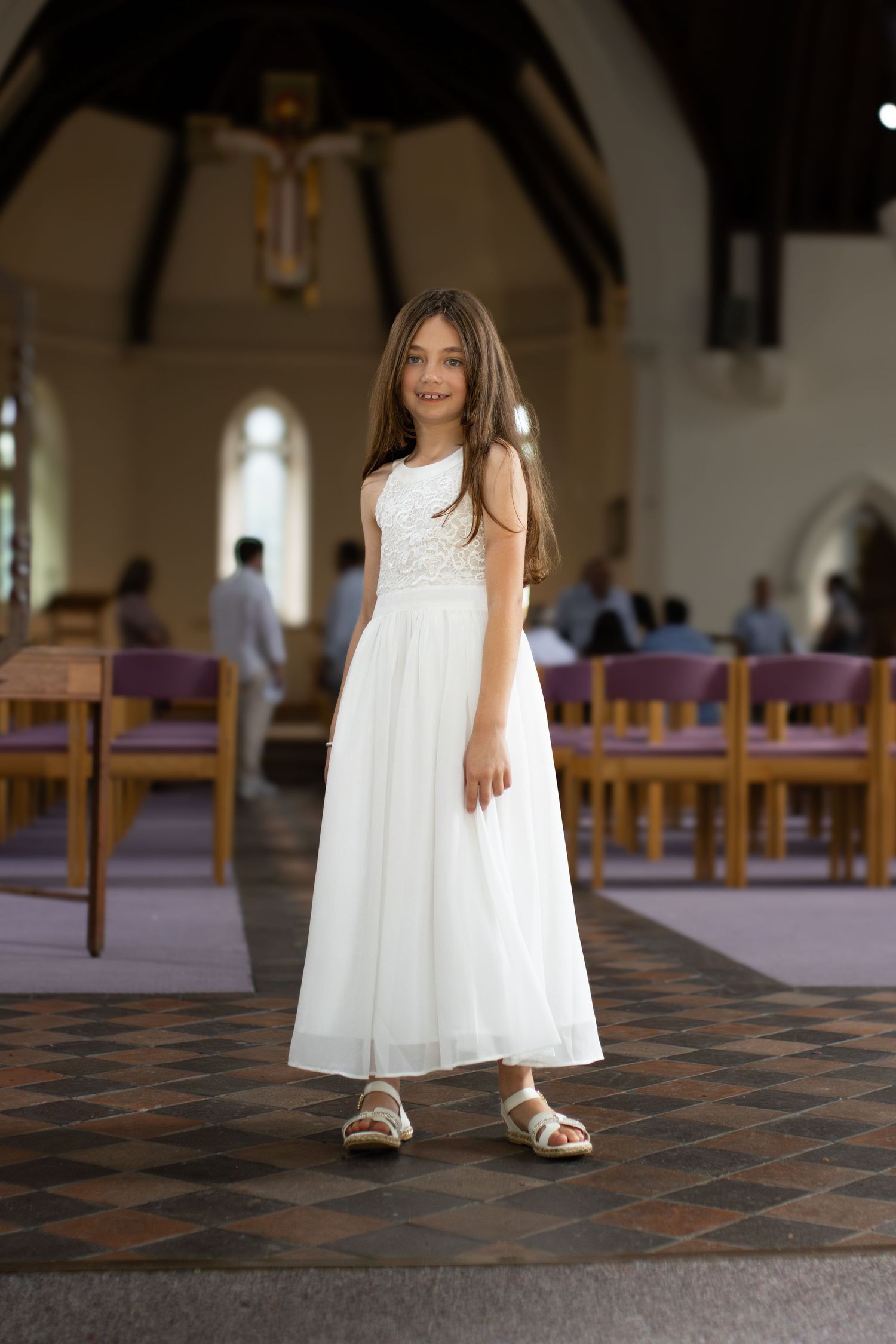 A white dress flows against a church's checkered floor during a ceremony.
