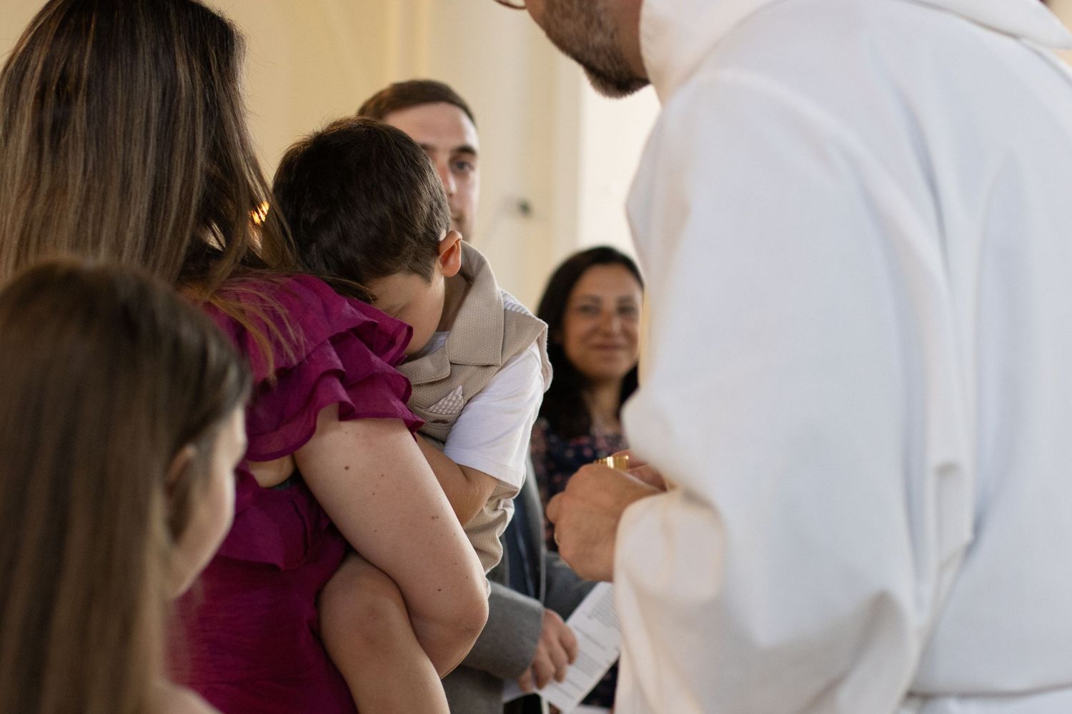A religious ceremony takes place in a traditional church setting with natural lighting.