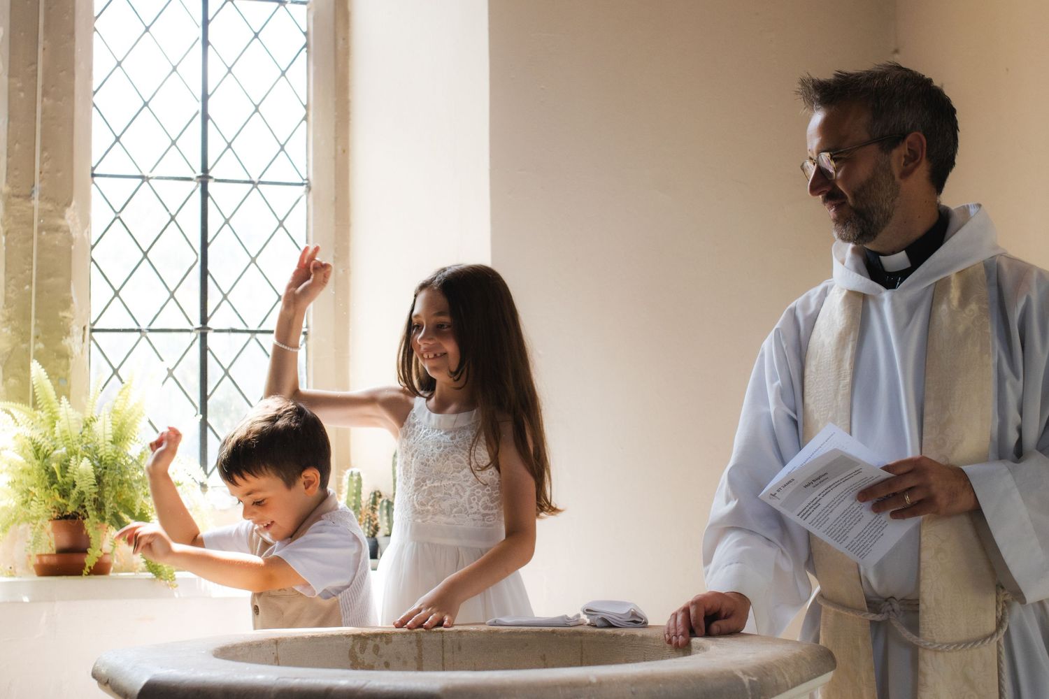 A religious ceremony takes place in a church with natural light streaming through windows.