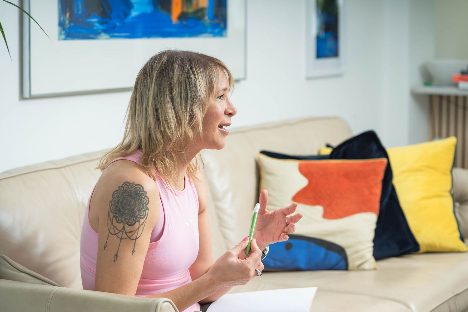 personal branding shoot Brighton a nutritionist sits on a chair she looks like she is talking to a client with a book on her lap and pen
