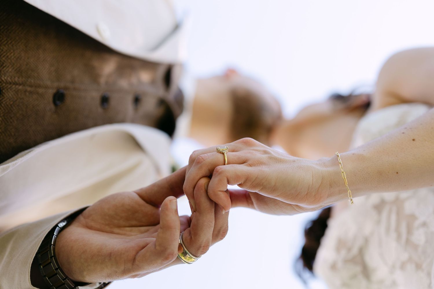 Bride and groom share first kiss at outdoor wedding ceremony with bridesmaids in olive gowns and groomsmen nearby.