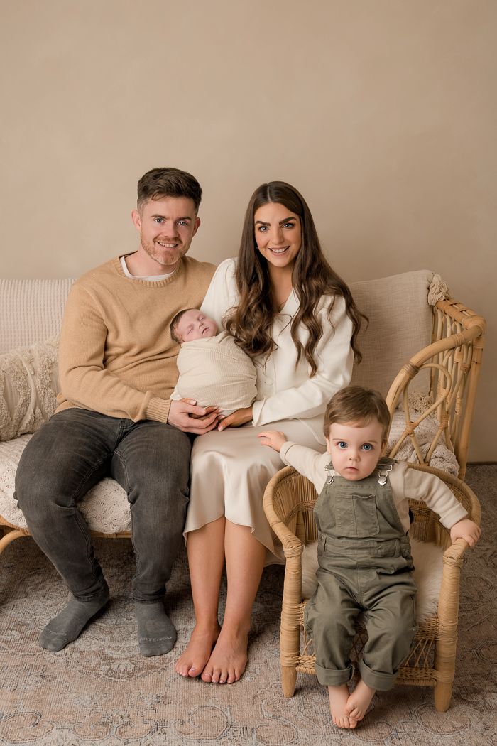 Family sitting together on vintage rattan chair in neutral tones for casual lifestyle photoshoot.