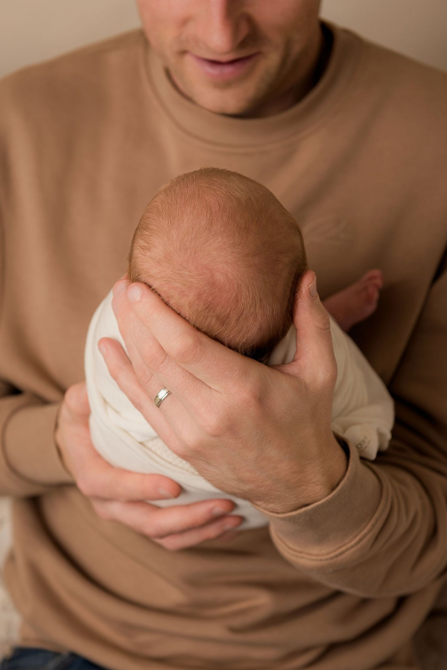 A series of five close-up photos showing dad's hands holding a small newborn baby.