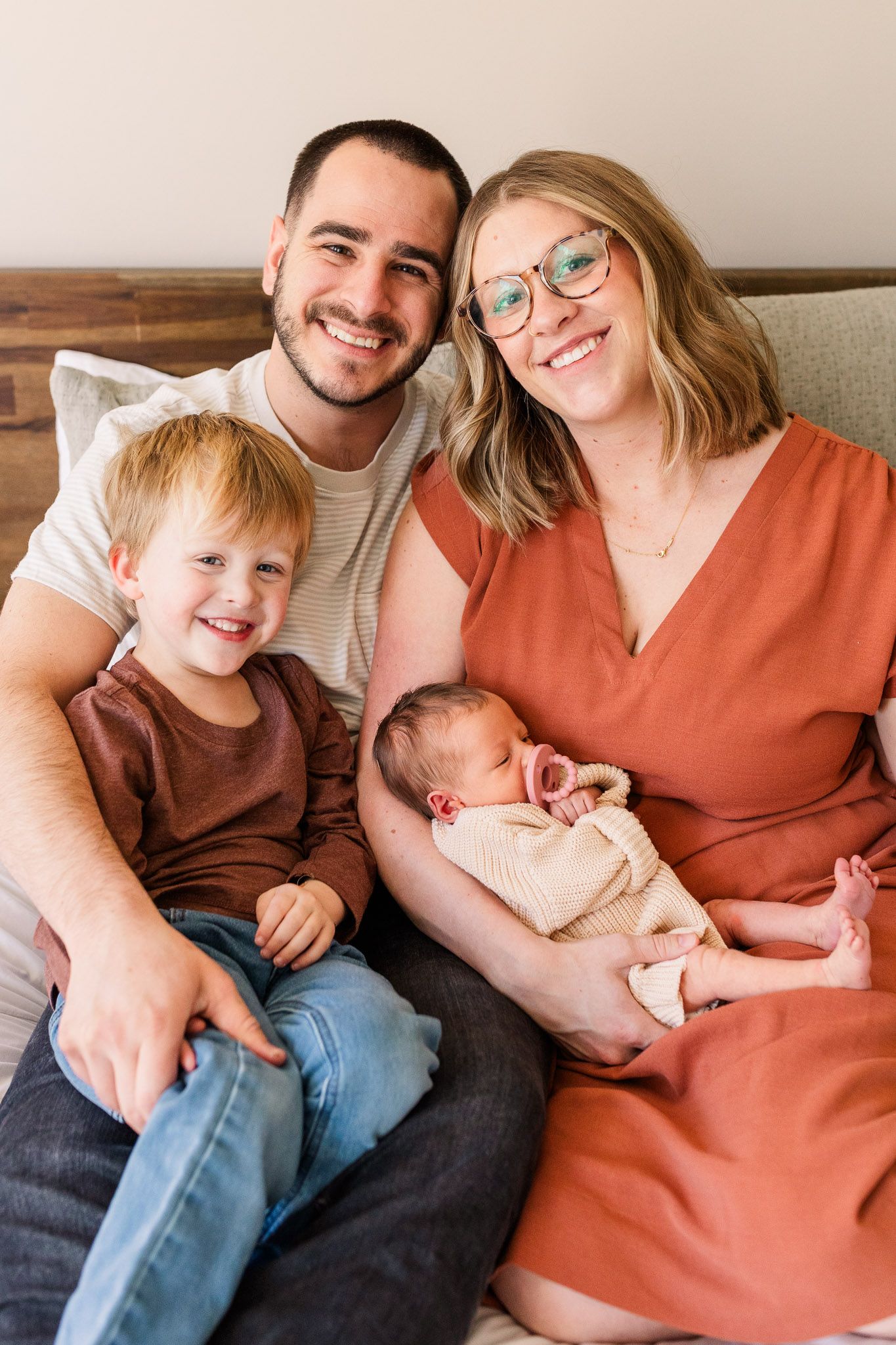 Richmond Virginia family and newborn photographer documents family snuggling new baby girl while smiling at the camera.