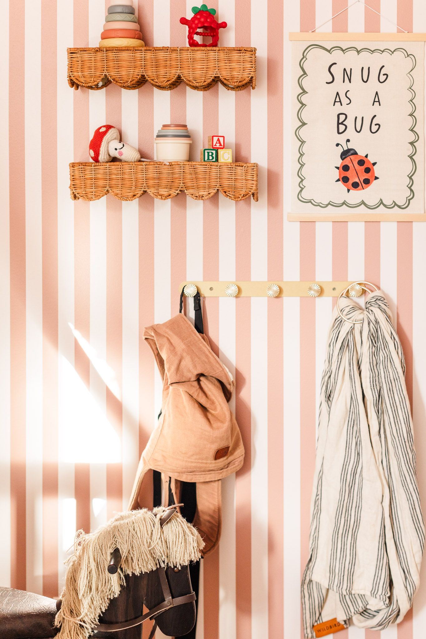 Baby nursery in Richmond Virginia with snug as a bug sign on the wall and Wild Bird baby carriers hanging around the classic cute baby toys.