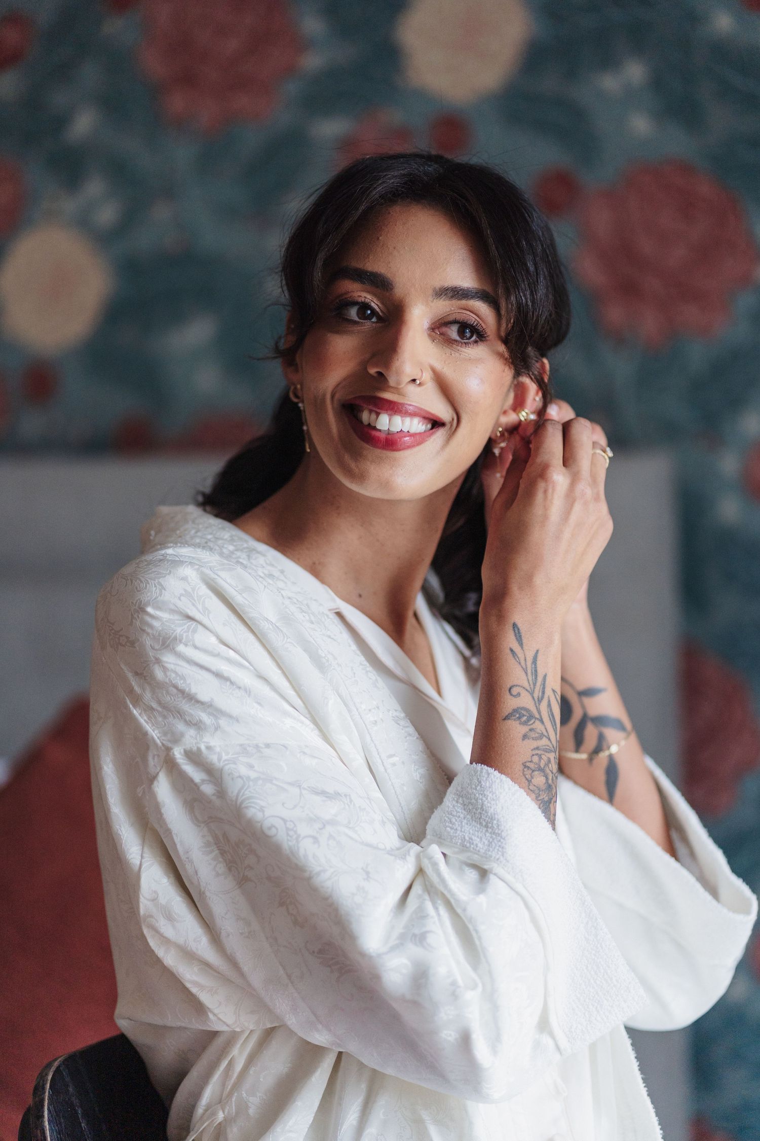 Person wearing white blouse smiling and posing against floral background in portrait series.