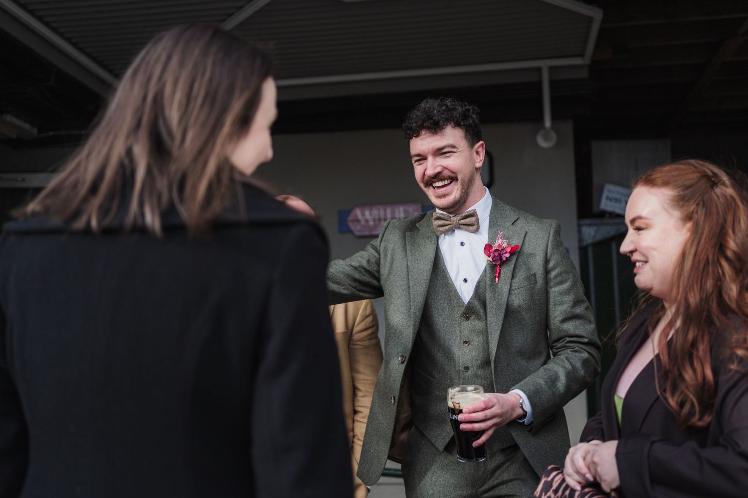 A group of people laugh and interact during what appears to be a theatrical performance or social gathering.