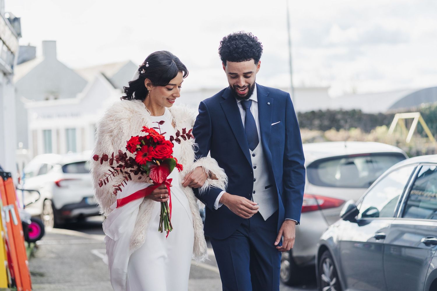 Newlywed couple walking along a marina dock with boats and water in the background on their wedding day.