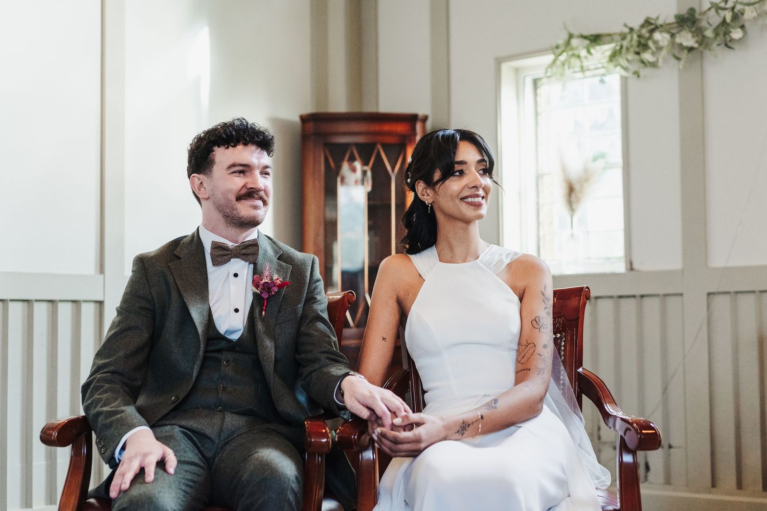 Wedding party sits and laughs together on wooden church pews during a joyful celebration.