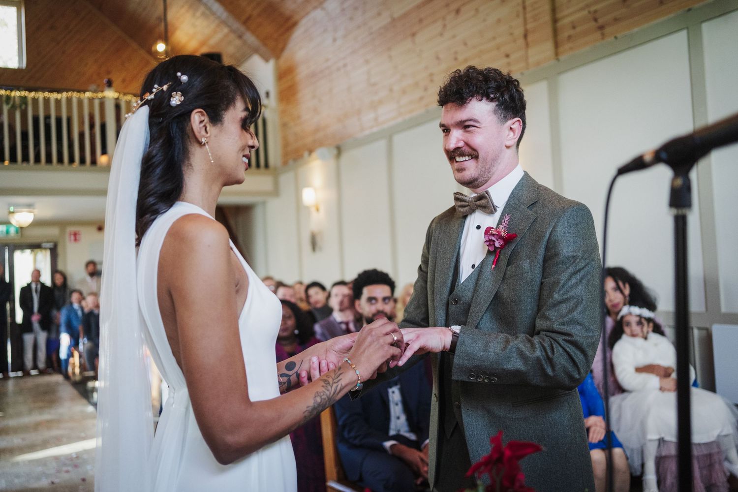 A couple shares a joyful moment during their wedding ceremony in a bright indoor venue.