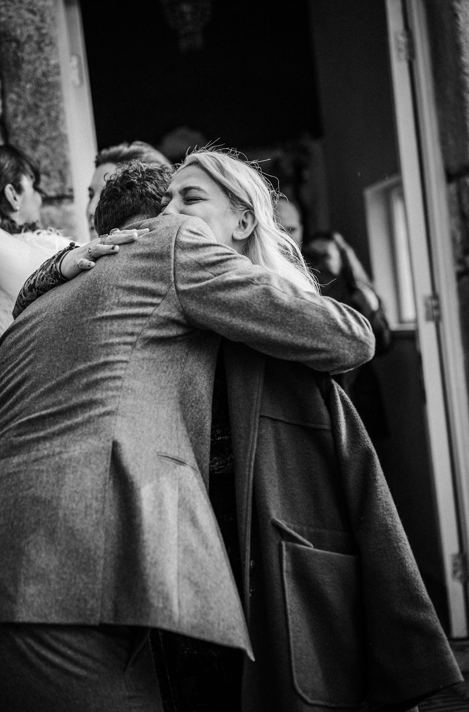 Black and white photo series showing two people in suits embracing in an emotional moment.