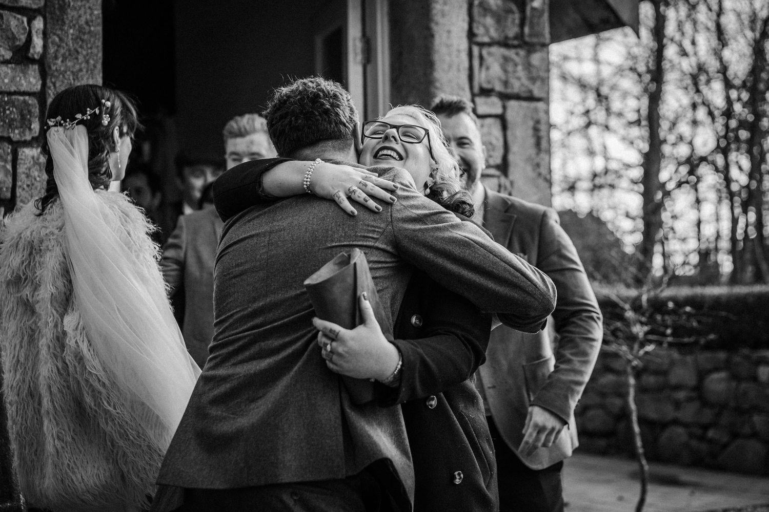 A black and white collage of wedding photos showing intimate embraces and emotional moments during a ceremony.